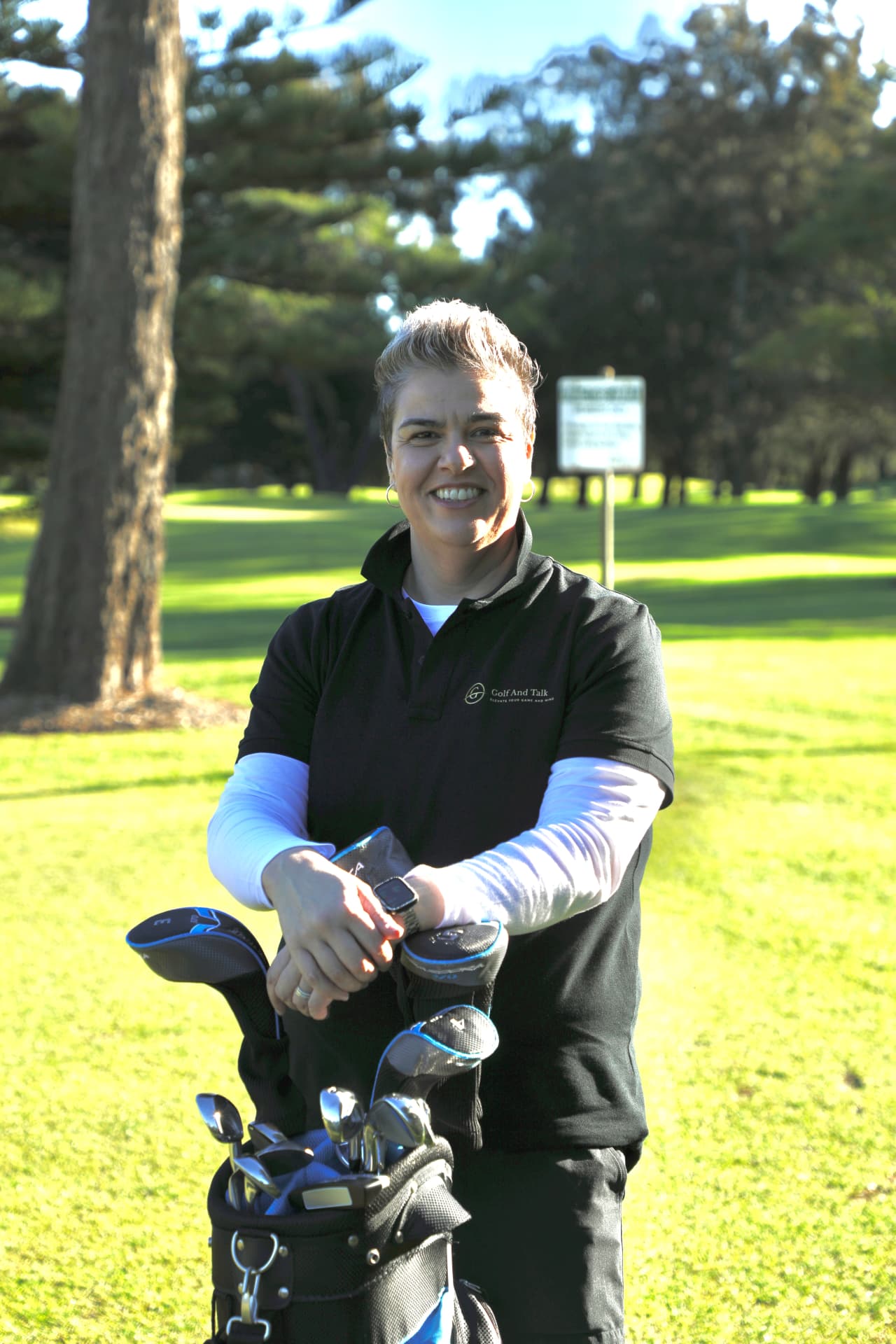 Evonne Englezos, founder of Golf And Talk, standing on the fairway beside her golf bag